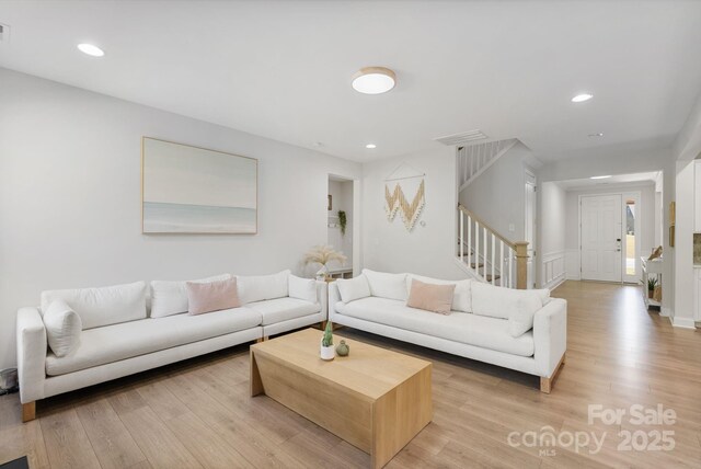 living room featuring recessed lighting, light wood-type flooring, stairs, visible vents, and a wainscoted wall