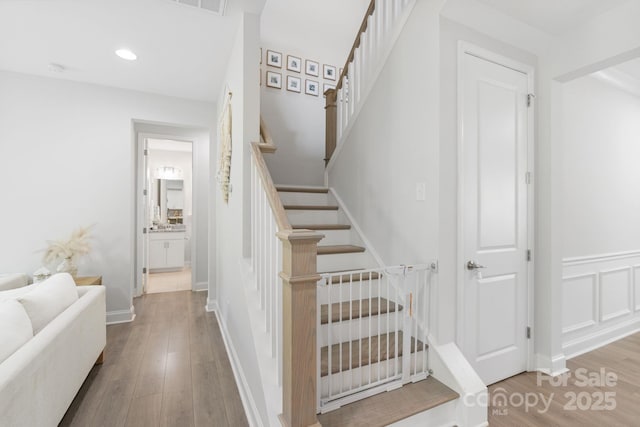 stairs featuring wood finished floors and recessed lighting