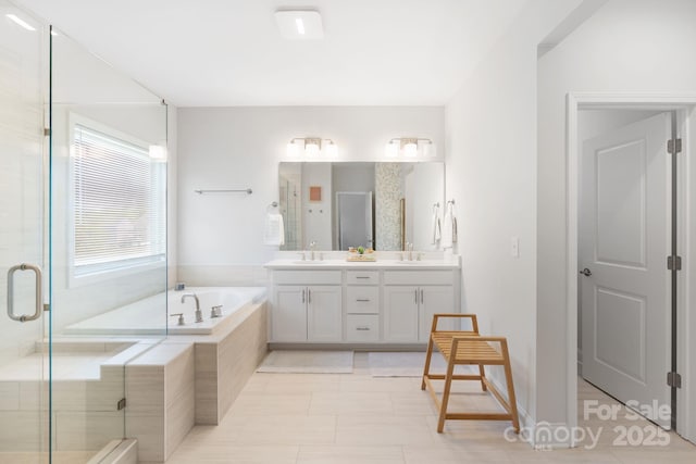 full bathroom featuring a shower stall, a garden tub, double vanity, and a sink