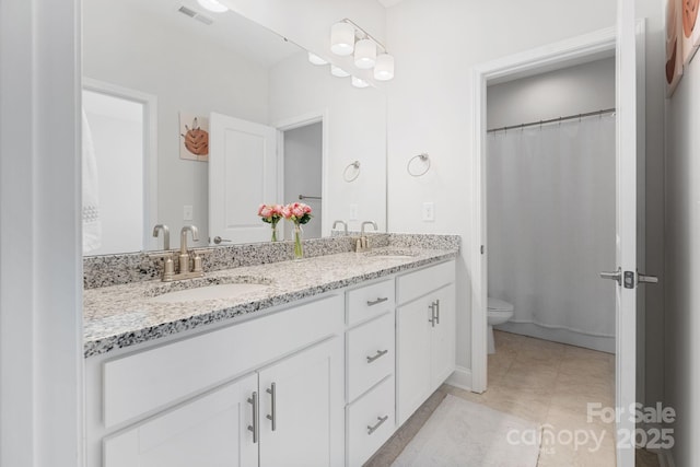 full bath featuring visible vents, toilet, double vanity, and a sink