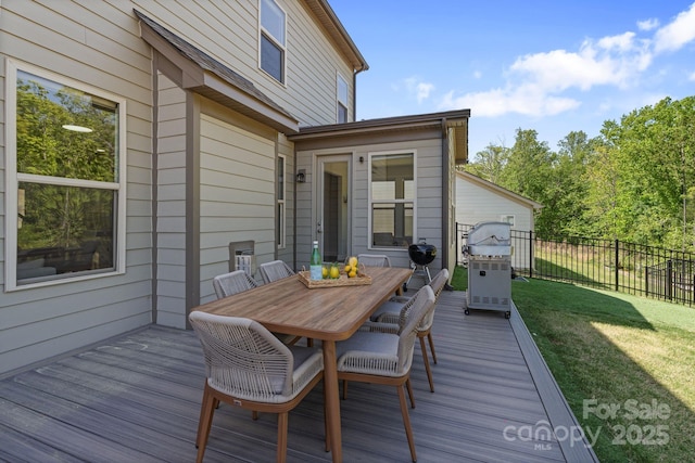 wooden terrace with fence, outdoor dining space, and a lawn