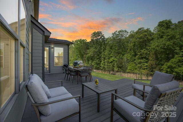 deck at dusk with outdoor lounge area, fence, and outdoor dining area
