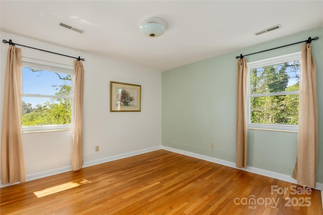 empty room featuring baseboards, visible vents, and light wood-style floors