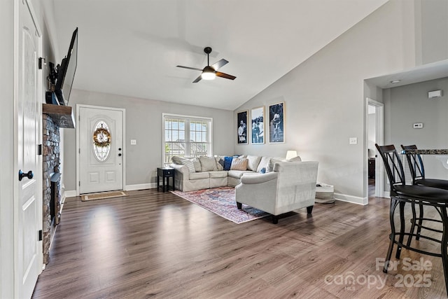 living room with a ceiling fan, high vaulted ceiling, wood finished floors, and baseboards