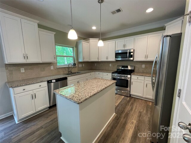 kitchen with crown molding, a sink, appliances with stainless steel finishes, and dark wood finished floors
