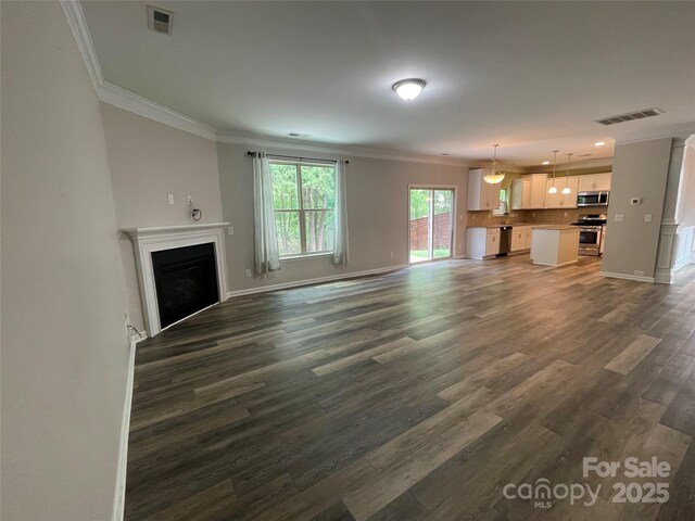 unfurnished living room with ornamental molding, visible vents, dark wood-style flooring, and a fireplace