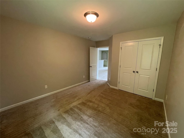 unfurnished bedroom with a closet, carpet floors, and baseboards