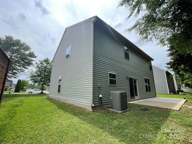 rear view of property featuring a lawn, central AC unit, and a patio area
