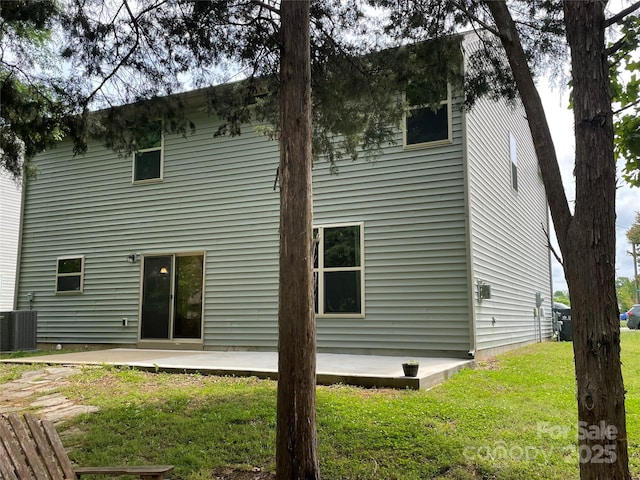rear view of house with central AC unit, a patio area, and a yard