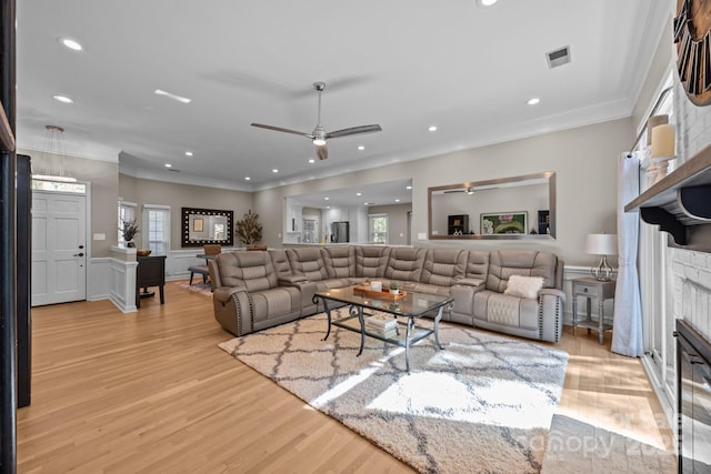living room with visible vents, light wood-style flooring, ceiling fan, and a glass covered fireplace