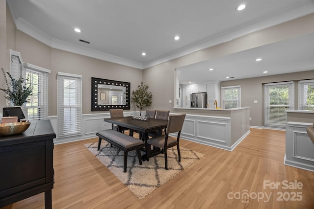 dining area with crown molding, wainscoting, light wood-style floors, recessed lighting, and visible vents
