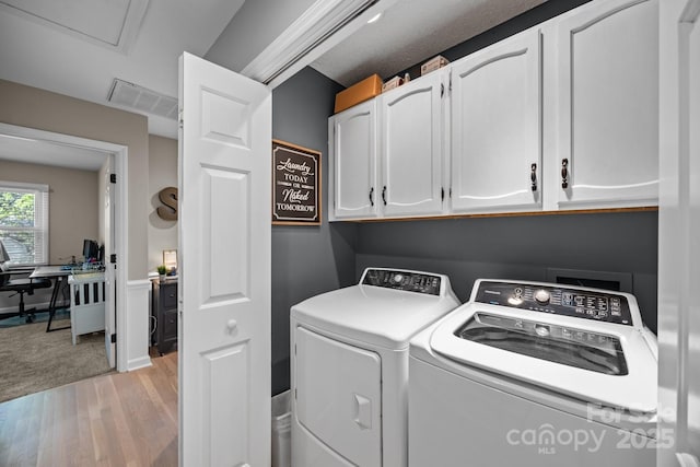 laundry room featuring visible vents, washer and clothes dryer, cabinet space, and light wood finished floors