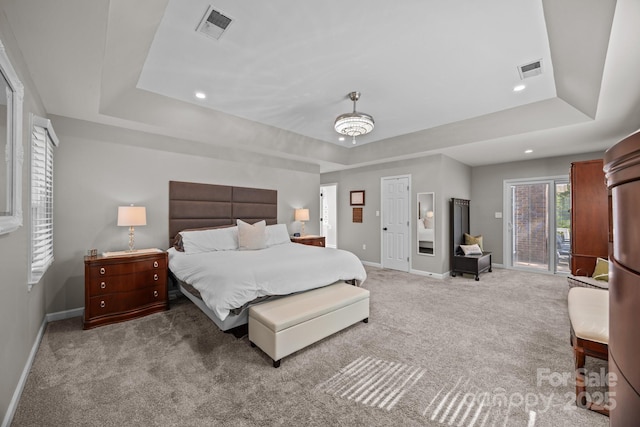 carpeted bedroom featuring visible vents, baseboards, and a tray ceiling