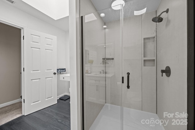 bathroom featuring baseboards, a shower stall, and wood finished floors