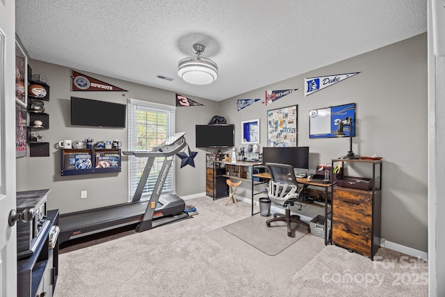 carpeted home office with baseboards, a textured ceiling, and visible vents