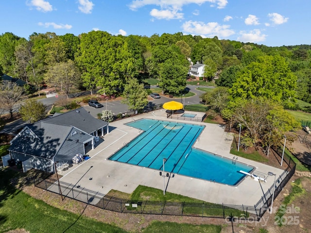 community pool with a patio area and fence