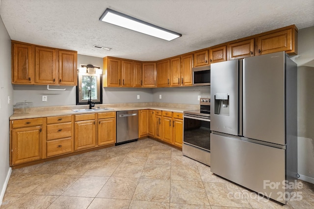 kitchen featuring brown cabinets, a sink, stainless steel appliances, visible vents, and light countertops