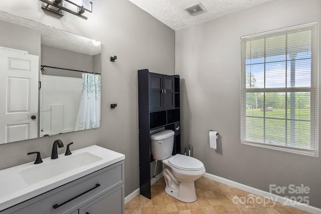 bathroom with a textured ceiling, toilet, baseboards, visible vents, and vanity