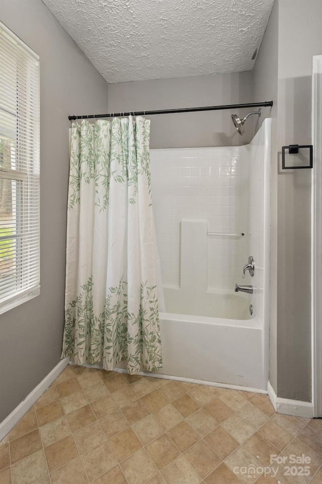 bathroom with a textured ceiling, shower / tub combo, and baseboards