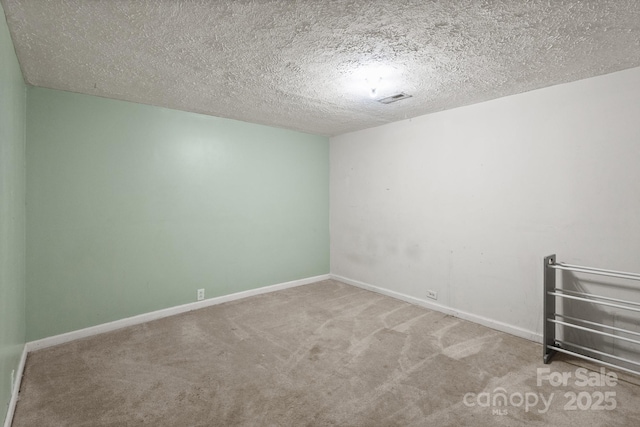 carpeted spare room featuring a textured ceiling, visible vents, and baseboards