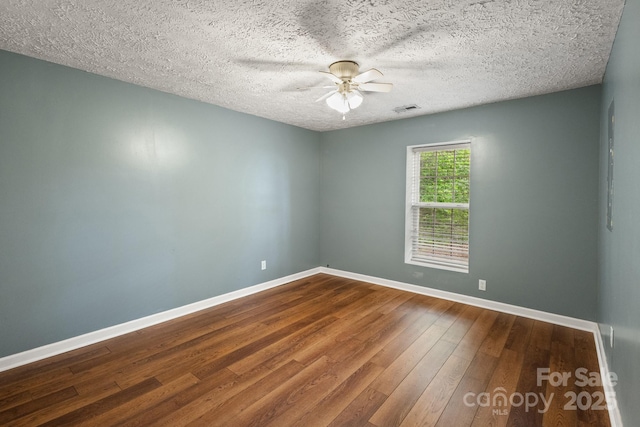 empty room featuring a ceiling fan, a textured ceiling, visible vents, baseboards, and hardwood / wood-style flooring