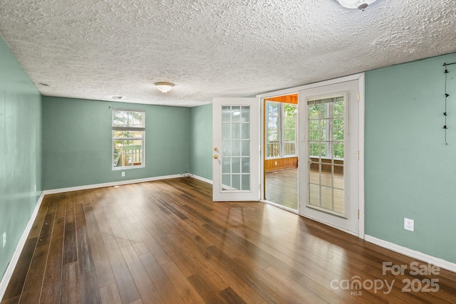 spare room featuring a textured ceiling, baseboards, and wood finished floors