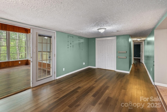 interior space featuring a textured ceiling, wood finished floors, and baseboards
