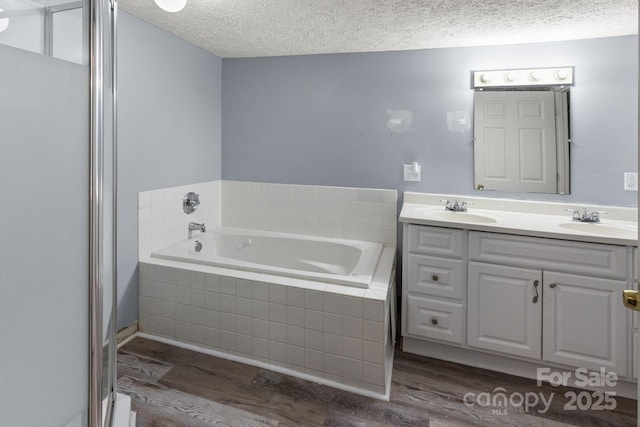 bathroom with a textured ceiling, a sink, and wood finished floors