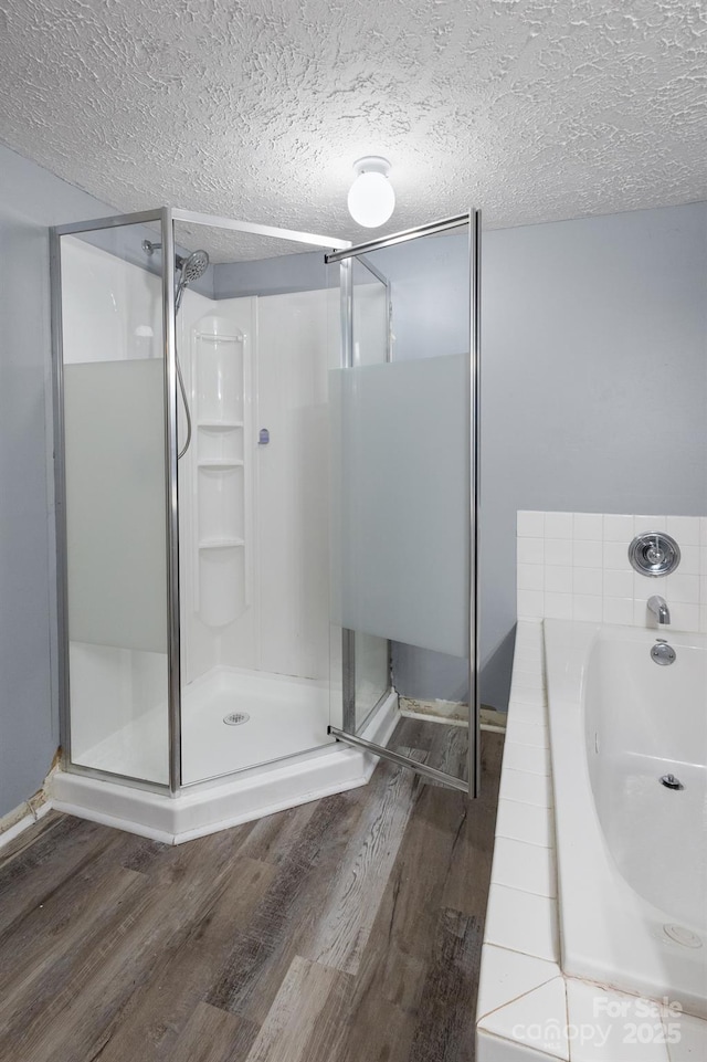 full bath with a stall shower, a textured ceiling, and wood finished floors