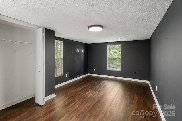 unfurnished bedroom featuring a textured ceiling, baseboards, and wood finished floors