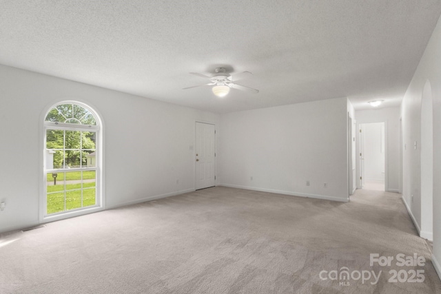empty room featuring a ceiling fan, a textured ceiling, light colored carpet, and visible vents
