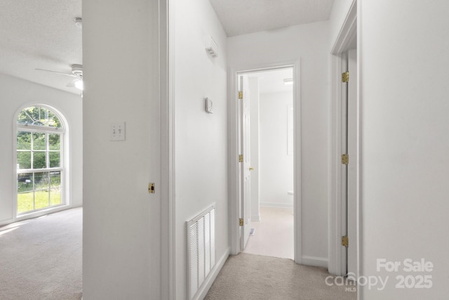 corridor with baseboards, visible vents, and carpet