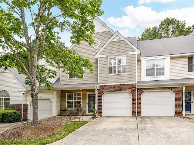 view of property with driveway, brick siding, and an attached garage