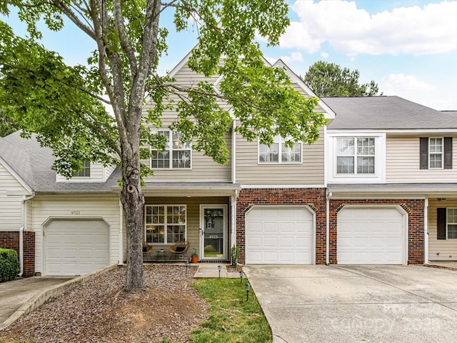 view of property with driveway, a garage, and brick siding
