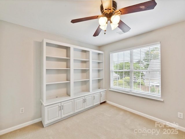 spare room with baseboards, light colored carpet, and ceiling fan