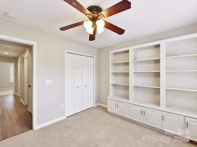 unfurnished bedroom featuring light carpet, baseboards, ceiling fan, and a closet