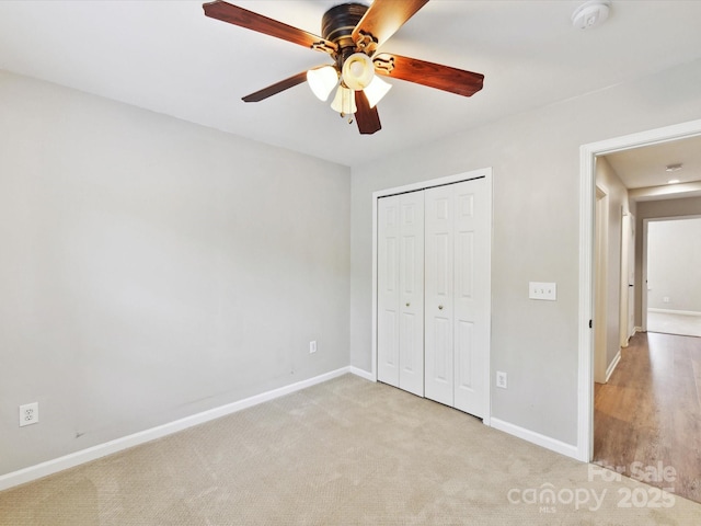 unfurnished bedroom featuring baseboards, a closet, and light carpet