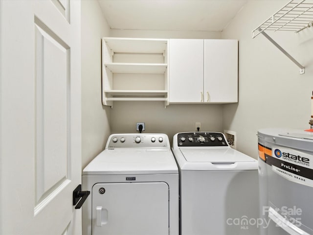 washroom featuring water heater, cabinet space, and washing machine and clothes dryer