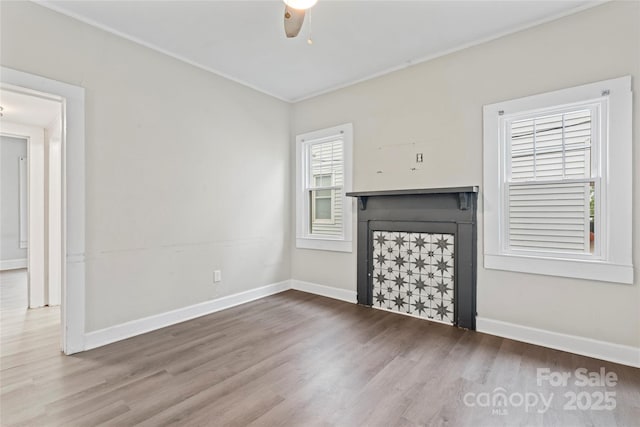 unfurnished living room featuring wood finished floors, crown molding, and a fireplace