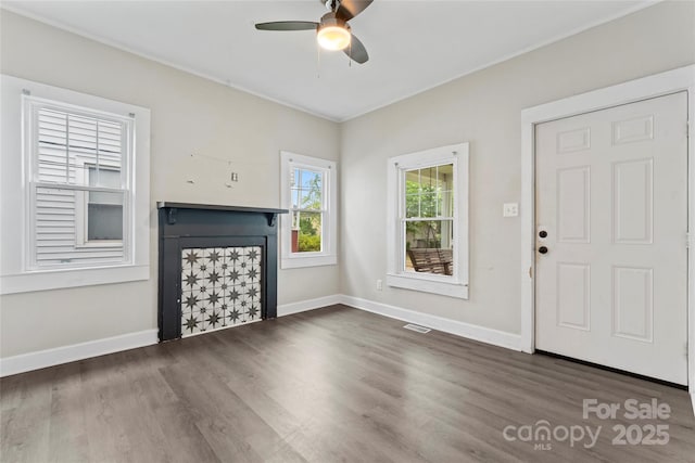 unfurnished living room featuring wood finished floors, a fireplace, baseboards, visible vents, and a ceiling fan