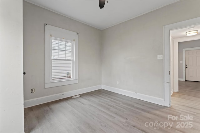 unfurnished room with crown molding, a ceiling fan, visible vents, baseboards, and wood finished floors