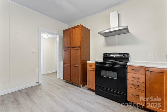 kitchen with light countertops, wall chimney range hood, brown cabinets, black electric range, and light wood finished floors