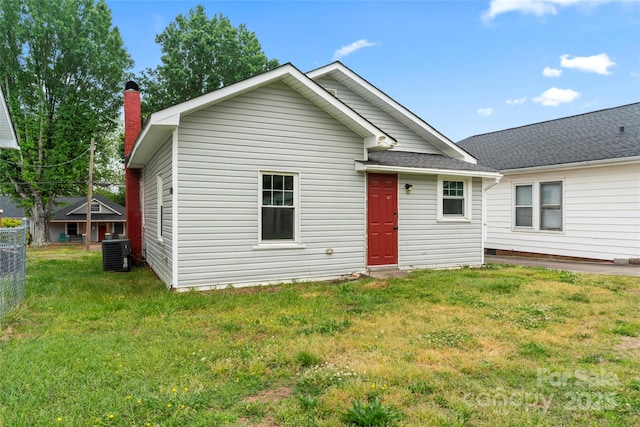 rear view of property featuring fence, a chimney, central AC unit, and a yard
