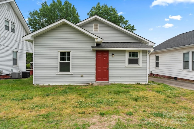 view of front of property with roof with shingles, central AC unit, and a front yard