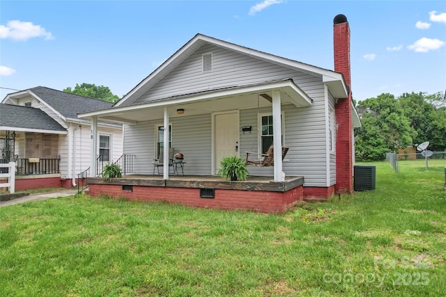 view of front of property featuring a porch, a front lawn, central air condition unit, and a chimney