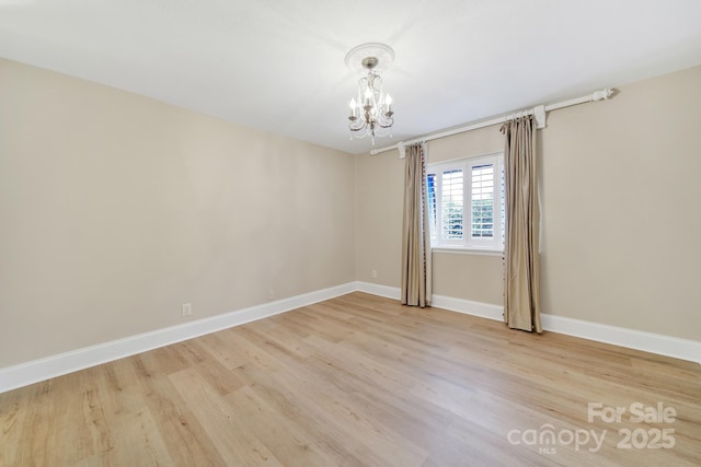 1323 Queens Rd Unit 420, Charlotte, NC 28207 - spare room featuring an inviting chandelier, light wood-style flooring, and baseboards