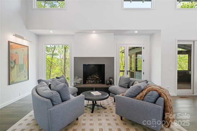 living area with plenty of natural light, wood finished floors, and a towering ceiling