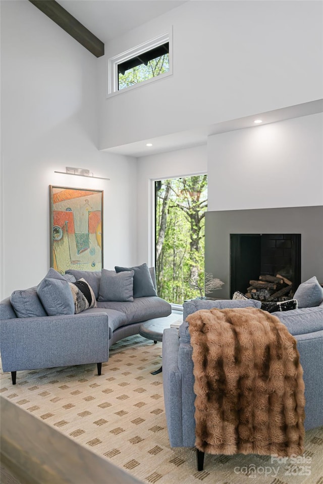 living room with a fireplace, beam ceiling, and a towering ceiling