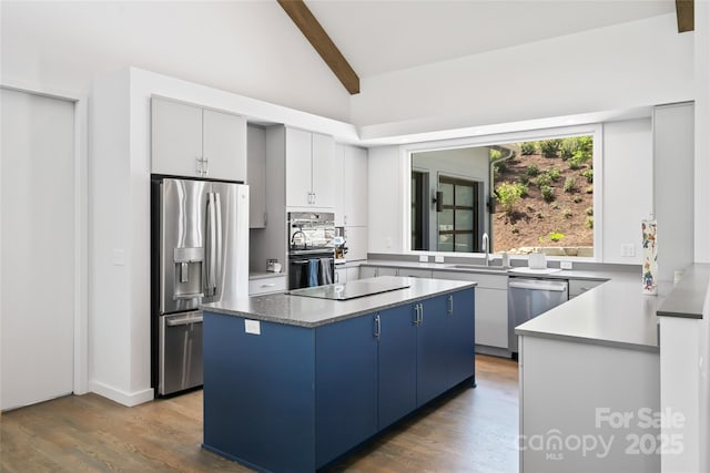 kitchen featuring a sink, beam ceiling, blue cabinetry, a center island, and stainless steel appliances