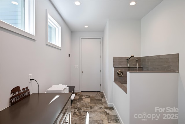 interior space with a walk in shower, recessed lighting, baseboards, and stone finish flooring